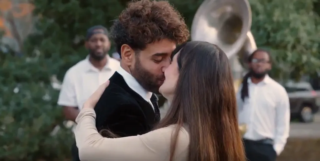 Mido kissing a woman on their wedding day as two men look on.
