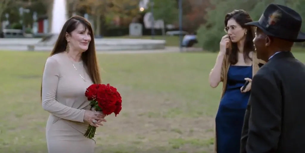 A woman in a beige dress holding red roses on her wedding day with Mido stealing the spotlight from Debby.