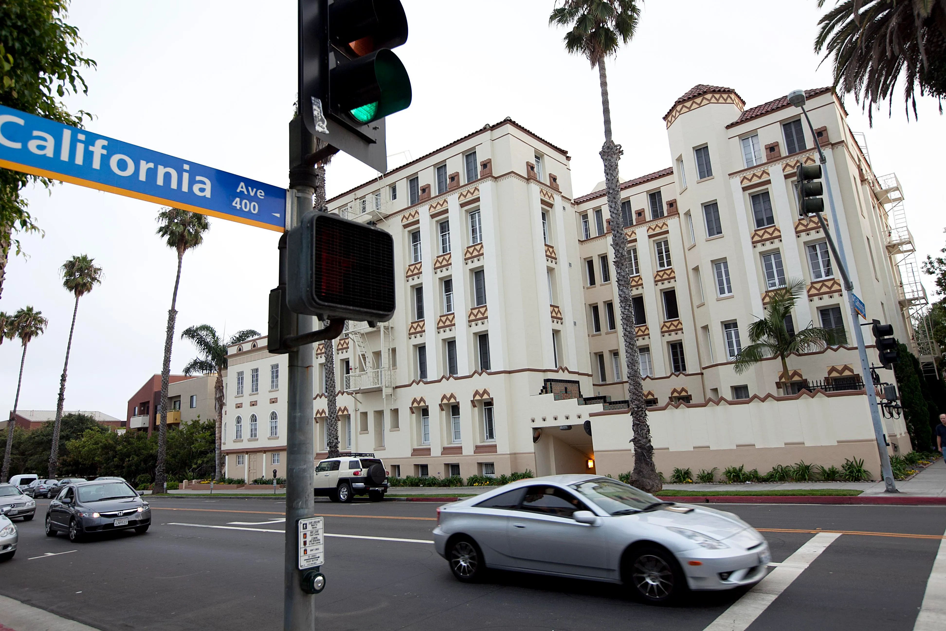 Cars pass a cream-colored historic apartment building with Art Deco details. 