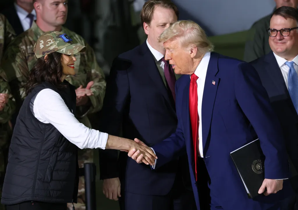 President Trump shaking hands with a woman wearing a camouflage cap at Selfridge Air National Guard Base.