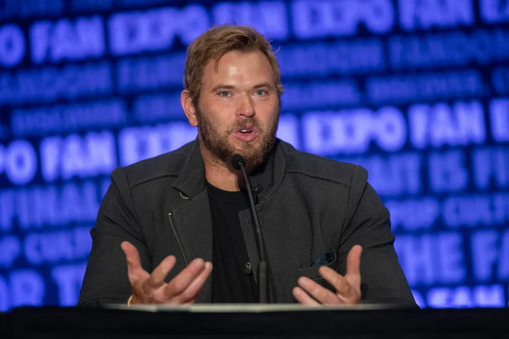Kellan Lutz speaking into a microphone at Fan Expo Denver.