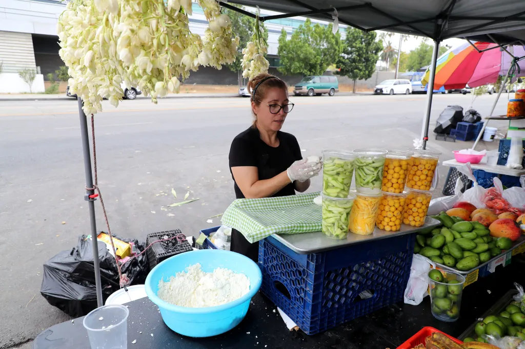 A food vendor prepares snacks at a stall along the Salvador Corridor in Los Angeles.