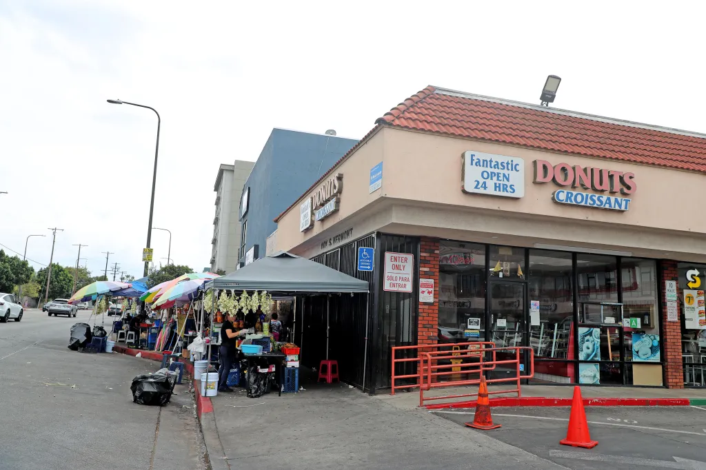 Food vendors with colorful umbrellas line the Salvador Corridor next to a donut shop.