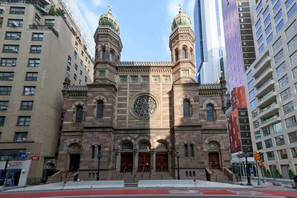 The Central Synagogue in New York City, featuring a large circular window and two prominent towers with golden domes.