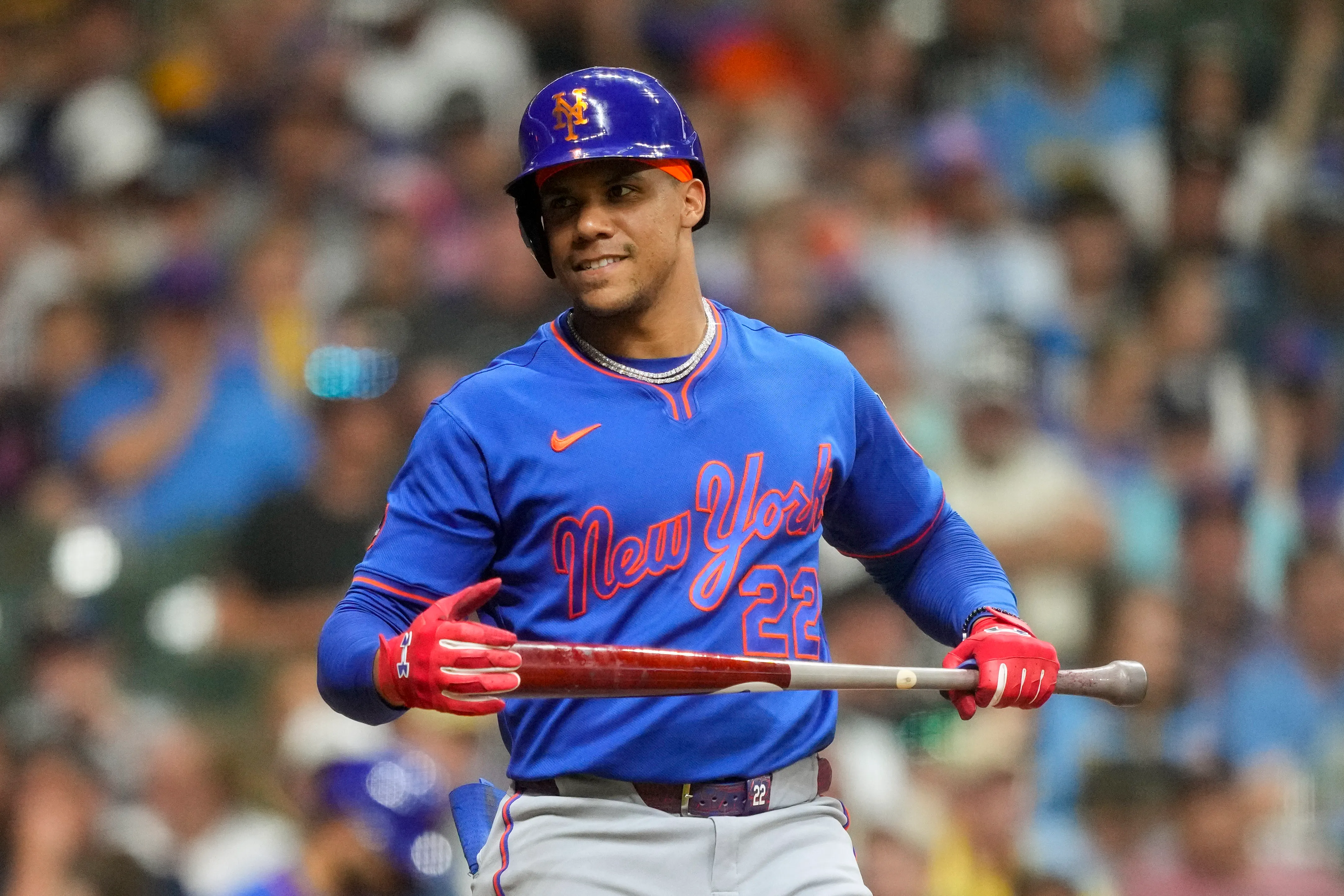 MLB player Francisco Alvarez, wearing a New York Mets uniform, holds a bat on the field during a game against the Milwaukee Brewers.