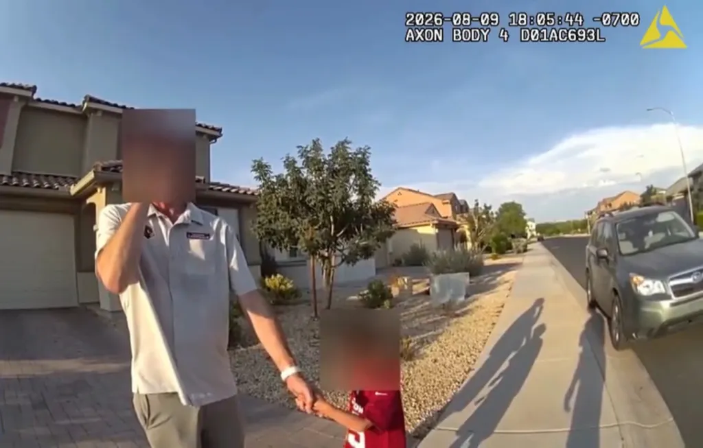 A man and child, whose faces are blurred, holding hands as they walk on a sidewalk in a residential neighborhood.