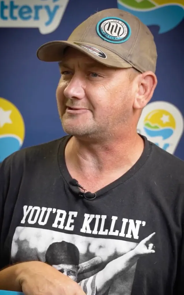 A man wearing a grey cap, a black shirt that reads 
