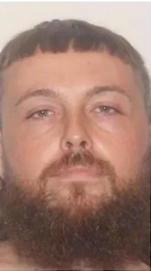 Mugshot of a man with a full beard and short hair.
