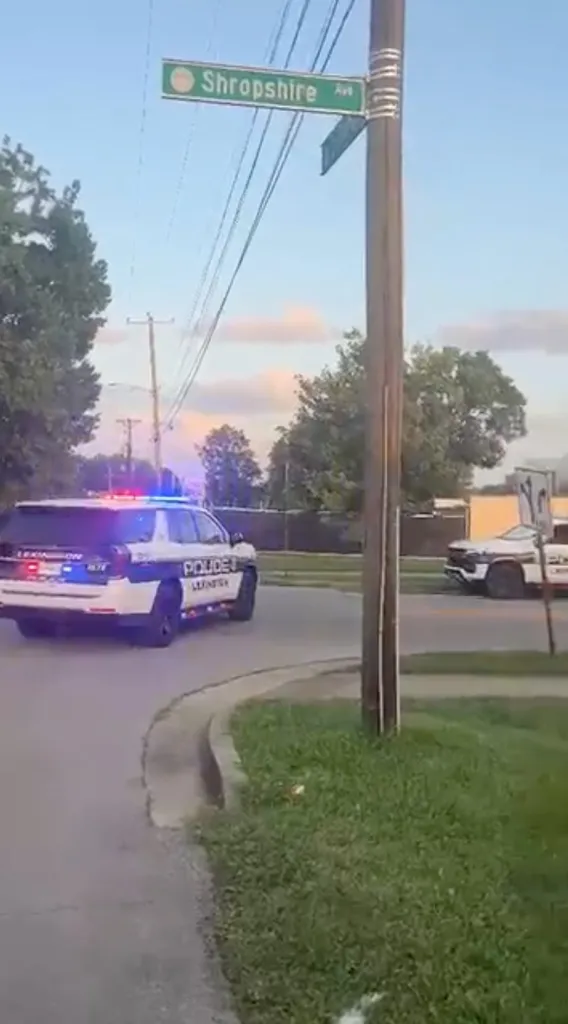 A police vehicle with flashing lights turns left at the intersection of Shropshire Avenue.