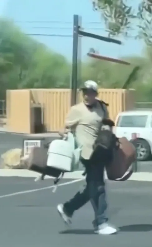 Man carrying multiple bags and a backpack as he runs down a street.