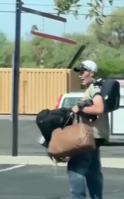 A white-haired woman with a purse holding a pistol in a parking lot.