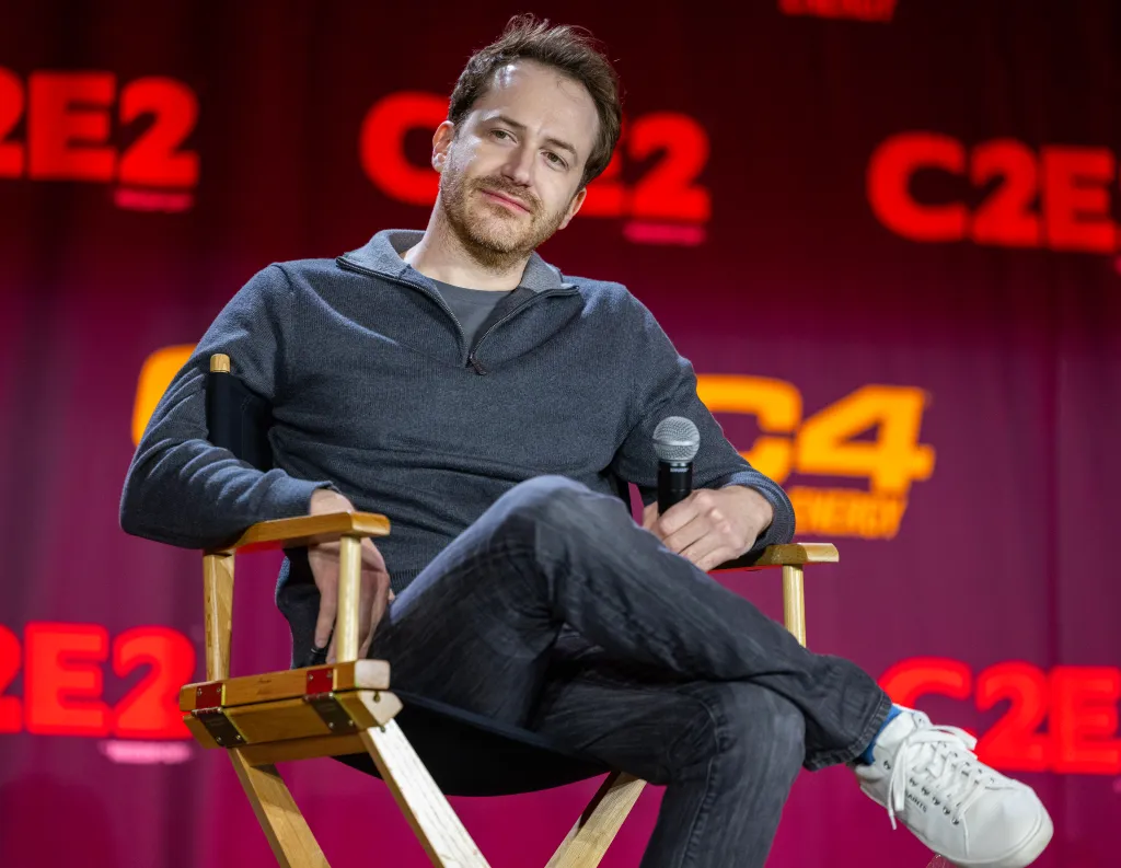 Actor Joseph Mazzello holding a microphone and sitting in a chair at C2E2.