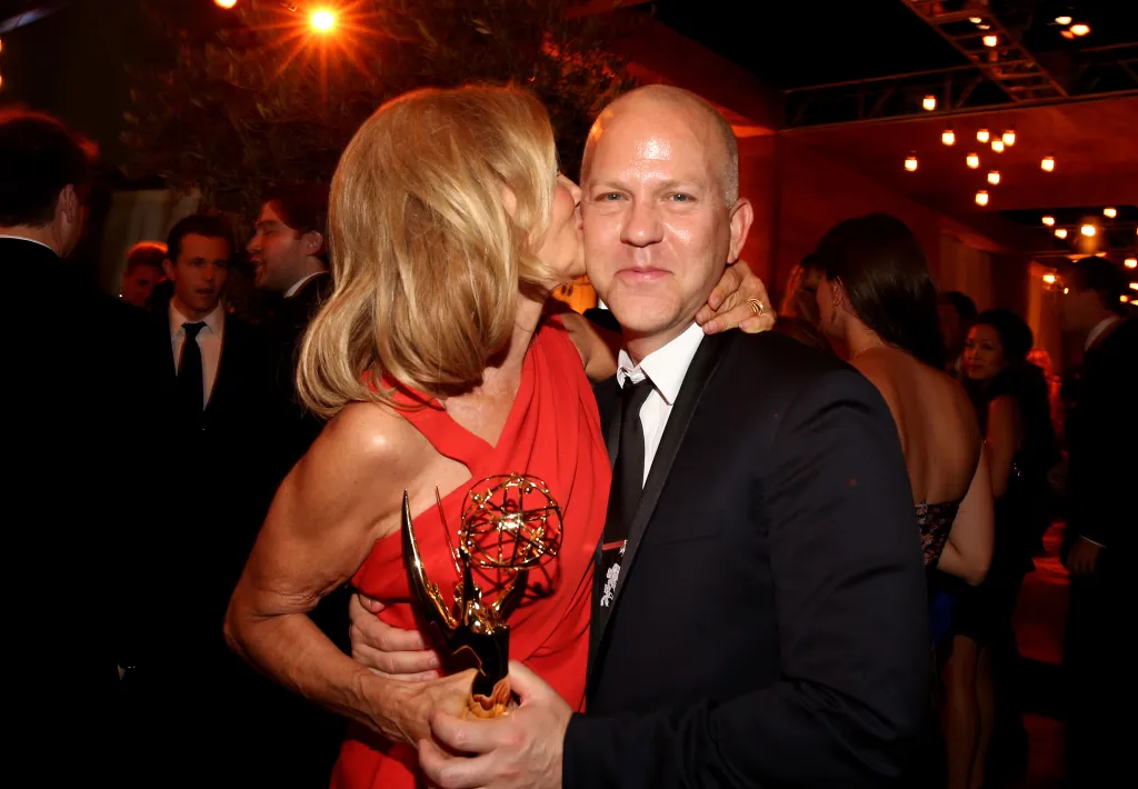 Actress Jessica Lange kisses producer Ryan Murphy's cheek as they hold an Emmy award.