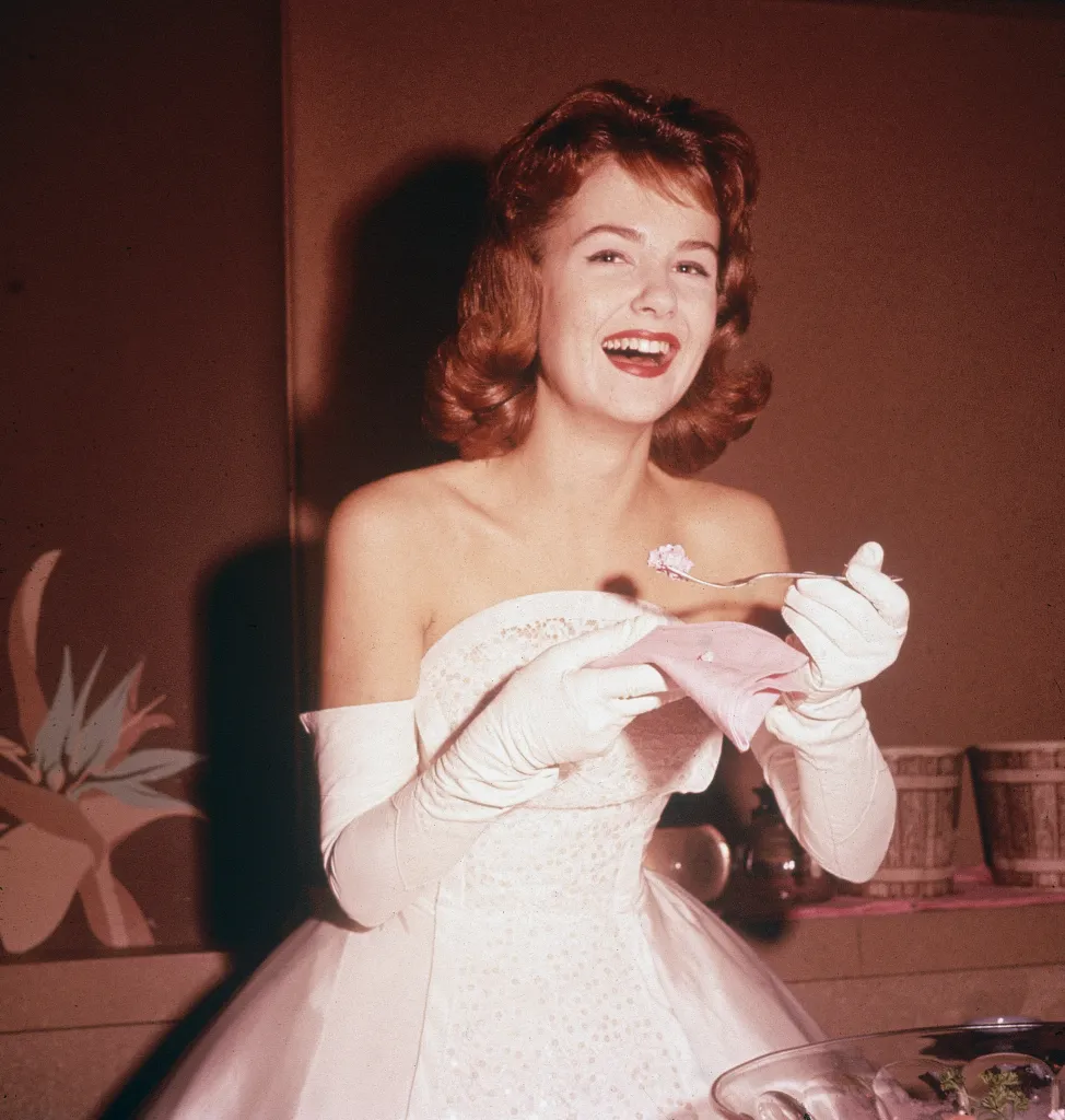 Actress Shelley Fabares laughing while eating a piece of cake at an event.