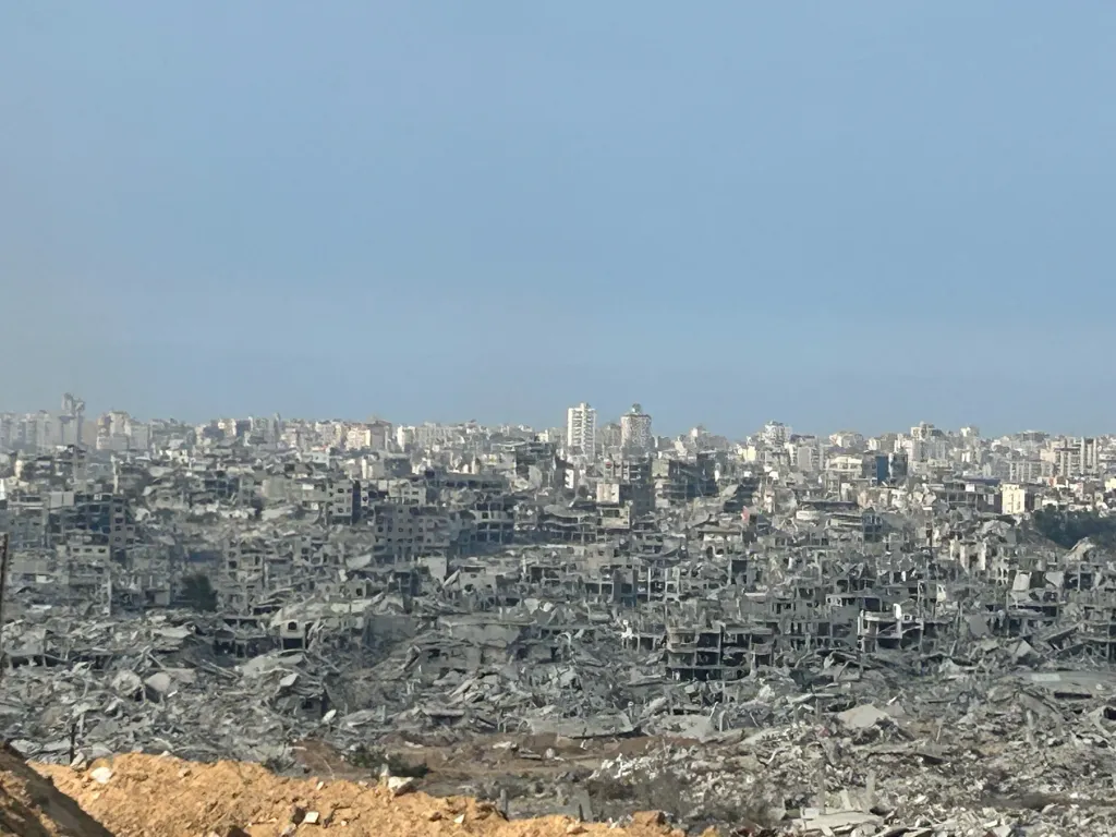 A city leveled to rubble and debris, with a few buildings still standing in the background.