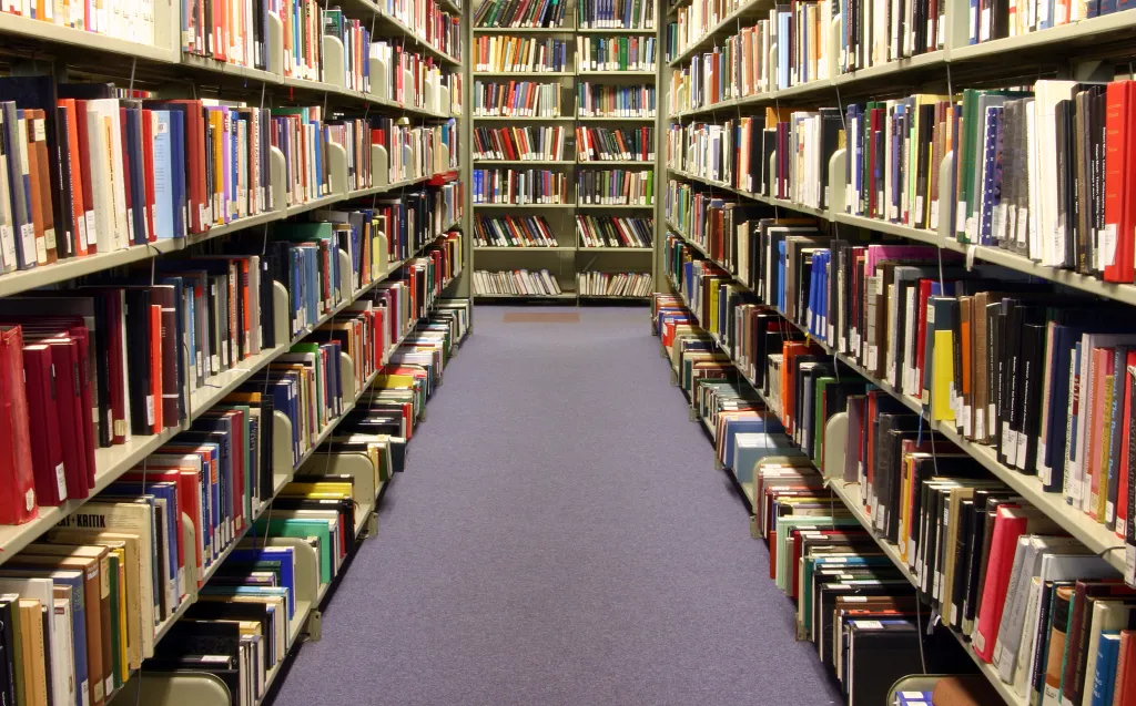 An aisle of bookshelves filled with books in a university library.