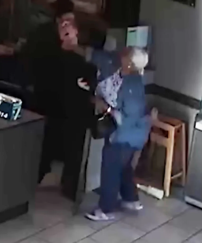 A blurry image of two people fighting, one wearing all black, the other in blue and white.