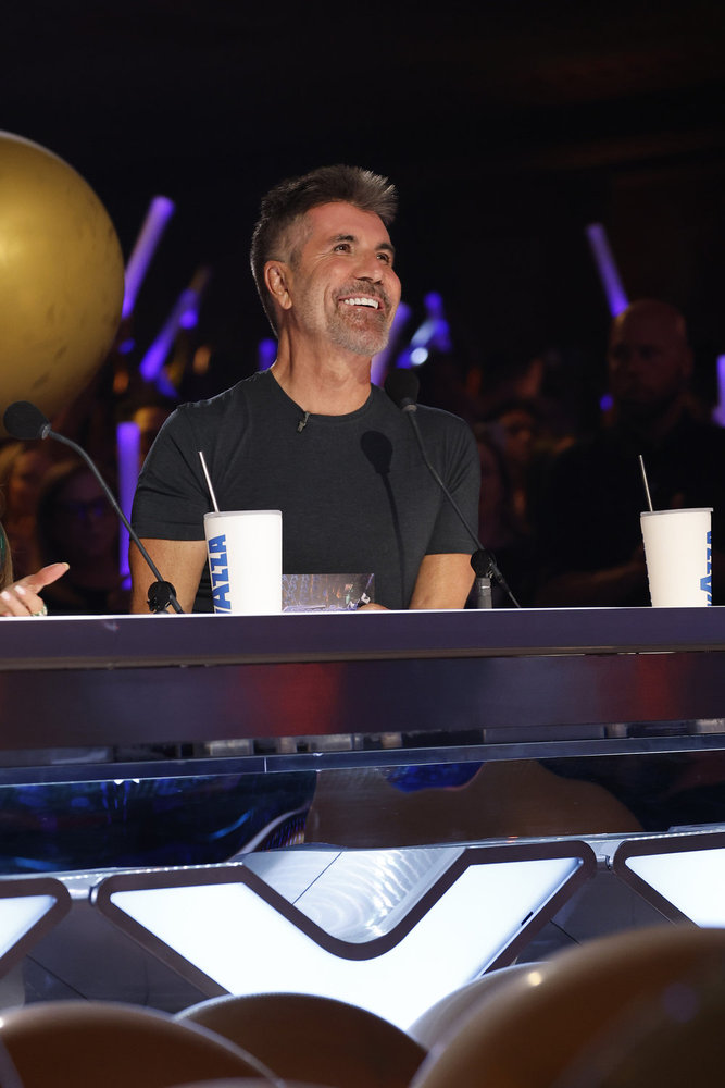 Simon Cowell smiling at the judges' table during 