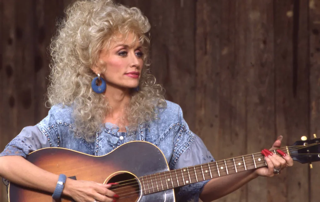 American country musician Dolly Parton playing a guitar.