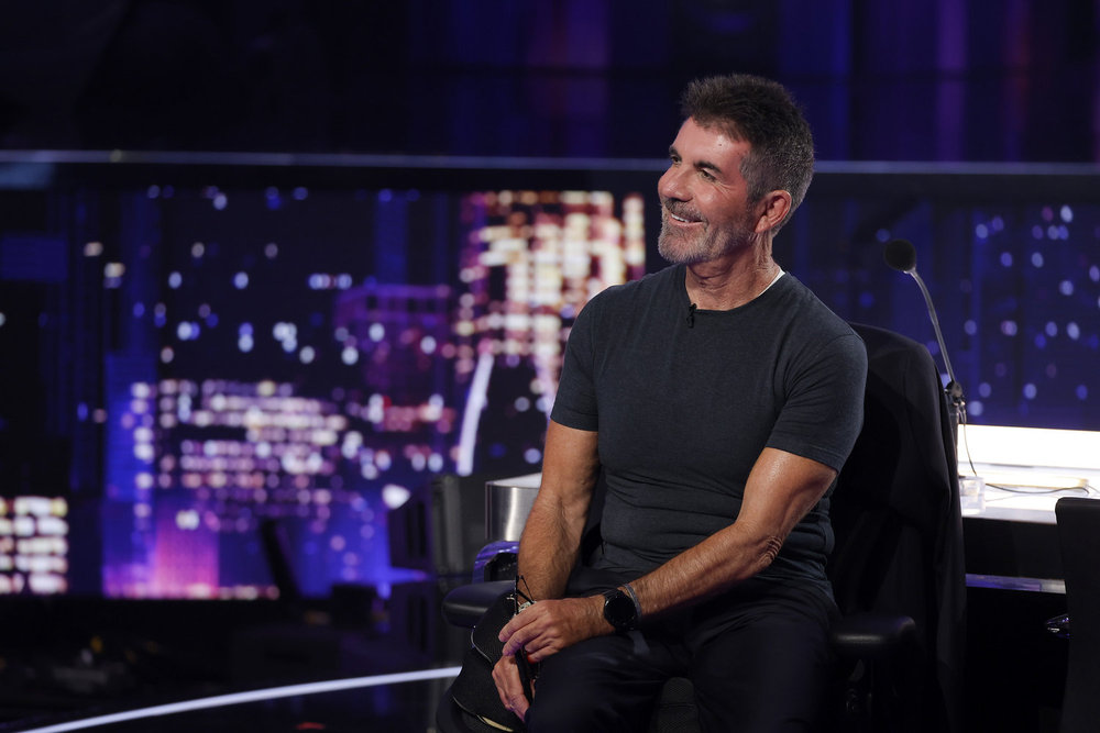 Simon Cowell smiling while seated on the set of 