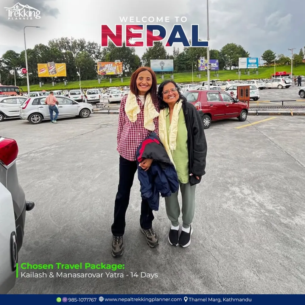 Amita Amin, 67, and Tejal Vyomesh Patel, 64, smiling in a parking lot with a 