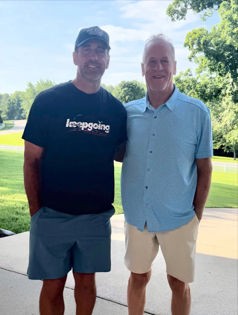 Aaron Rodgers and a man pose together outdoors.