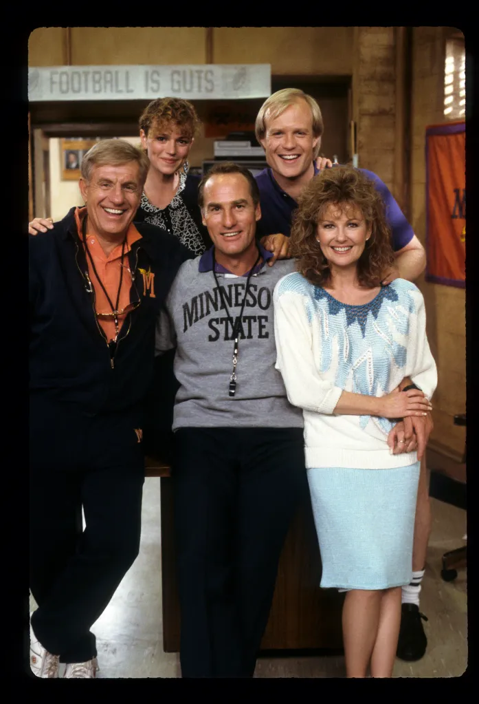 The cast of Coach smiling at the camera.