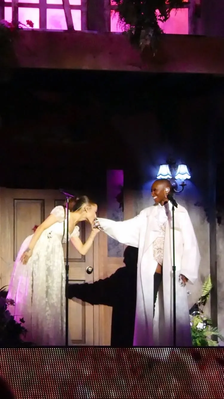 Ariana Grande kisses Cynthia Erivo's hand during a performance.