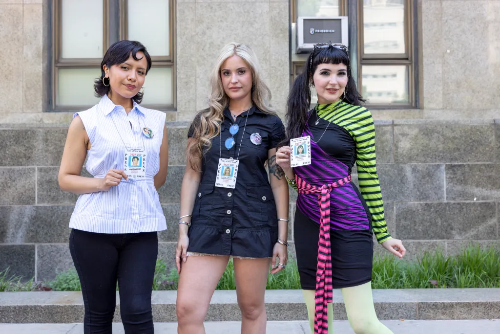 Ashley Rojas, Abril Rios, and Lena Weissbrot pose with press credentials and pins supporting Luigi Mangione outside Manhattan Court.
