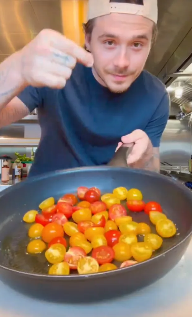 Brooklyn Beckham adding cherry tomatoes to a pan with oil.