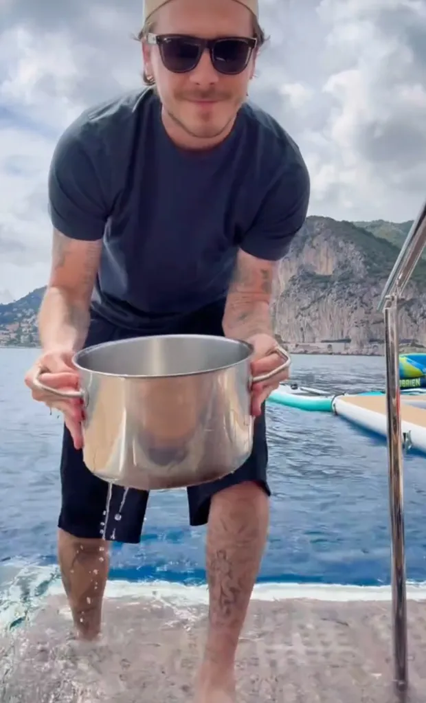 A man on a boat collecting seawater in a pot.