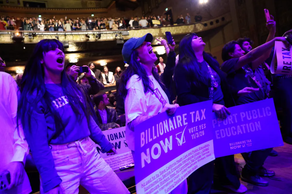 Attendees cheering and holding signs that read 