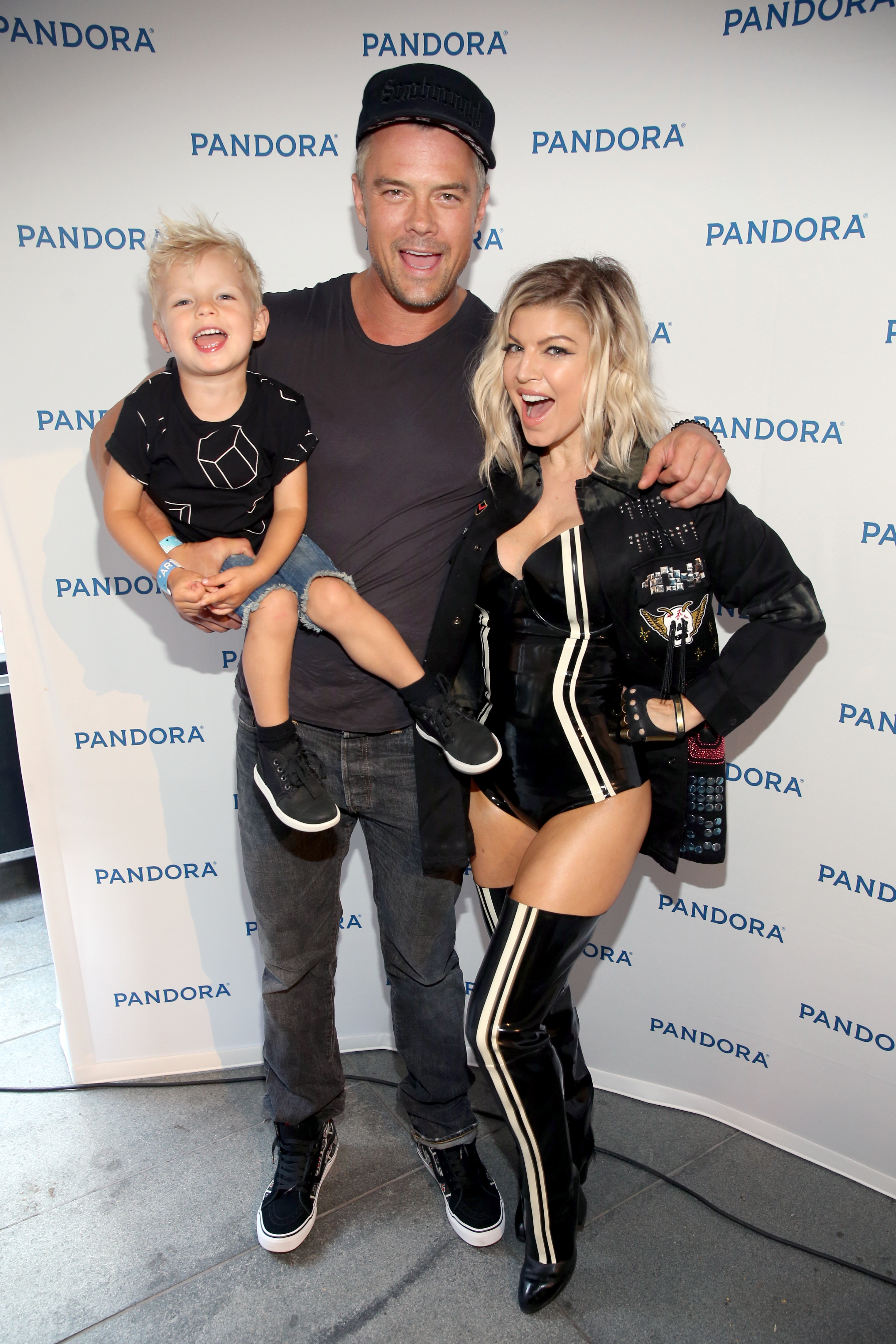 Actor Josh Duhamel holds his son, Axl Jack Duhamel, as singer Fergie stands next to them at the Pandora Summer Crush event.