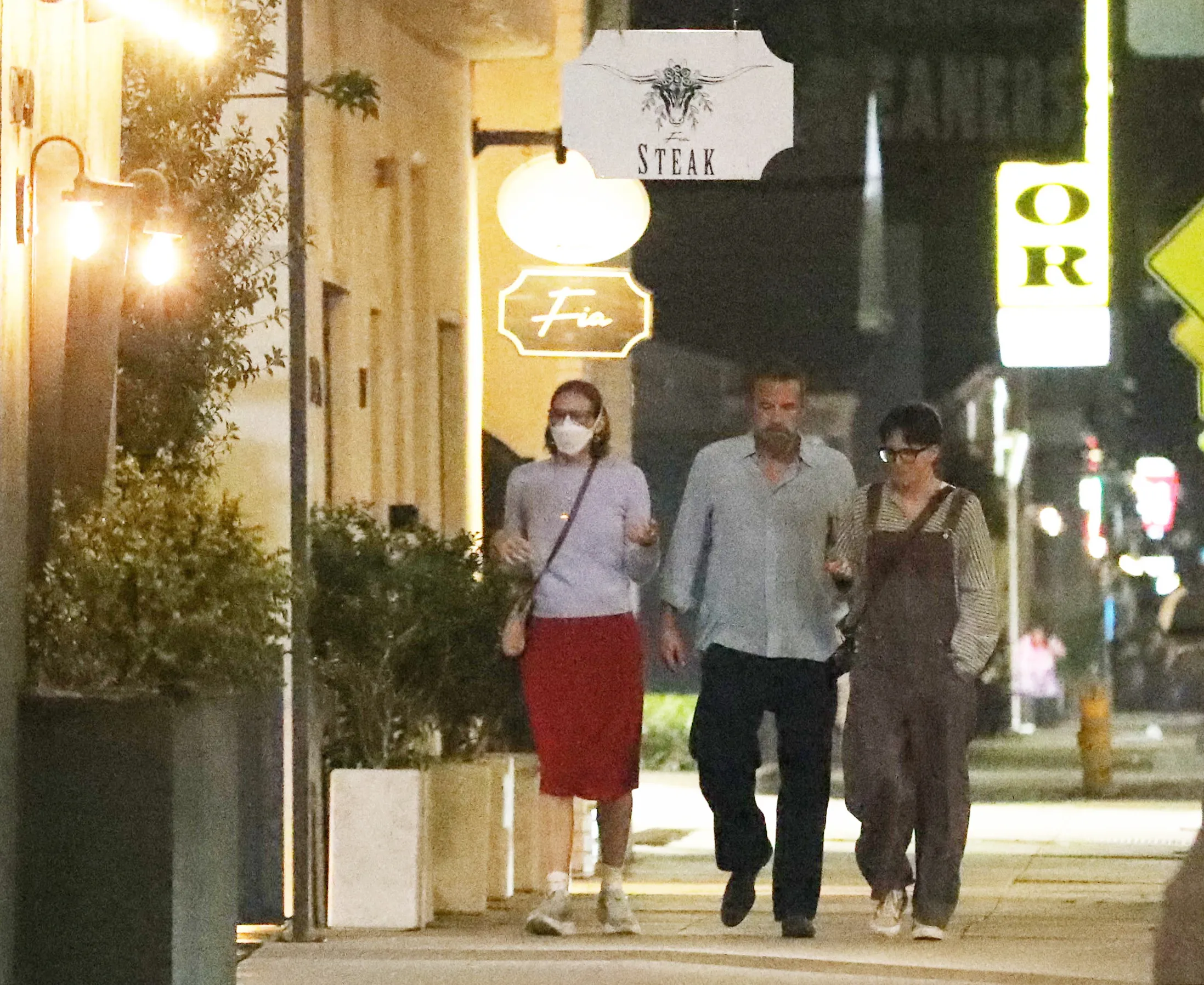 Ben Affleck and his two children walk down a street at night.