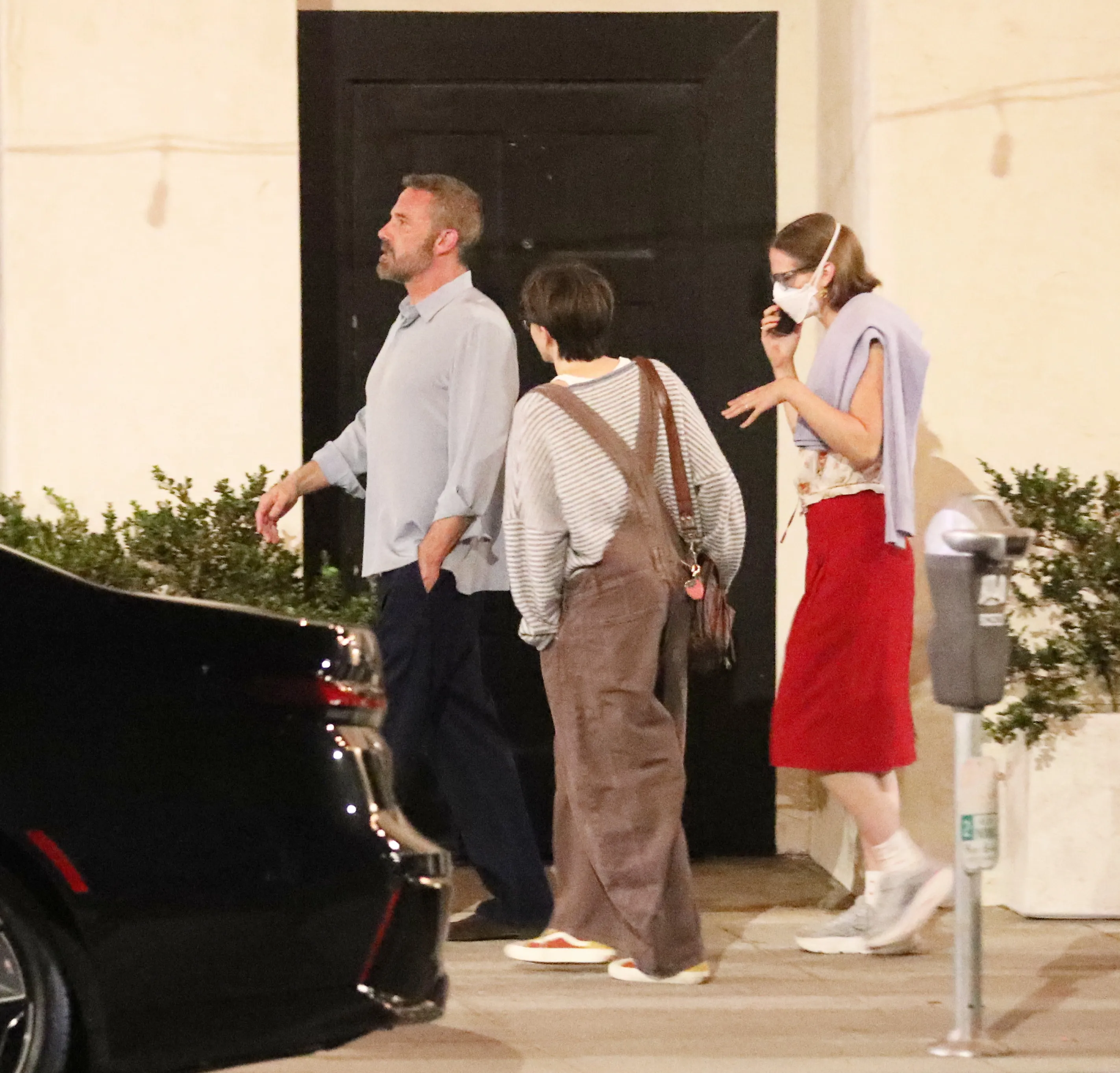 Ben Affleck walking with his kids, one of whom is masked, near a restaurant.