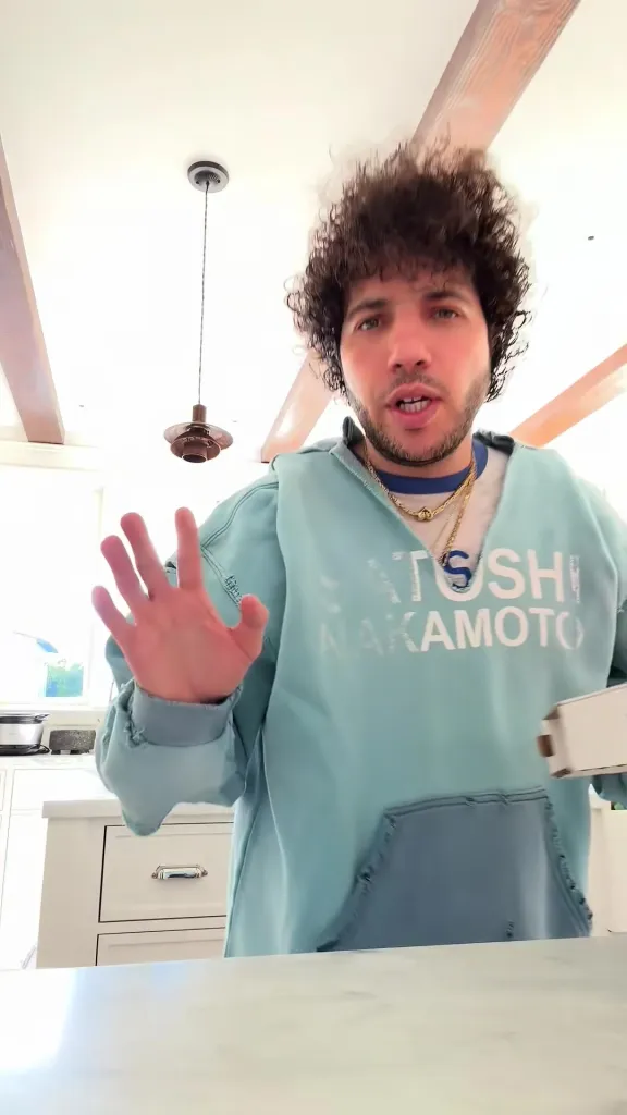 Benny Blanco, a man with curly hair and a light blue sweatshirt with 