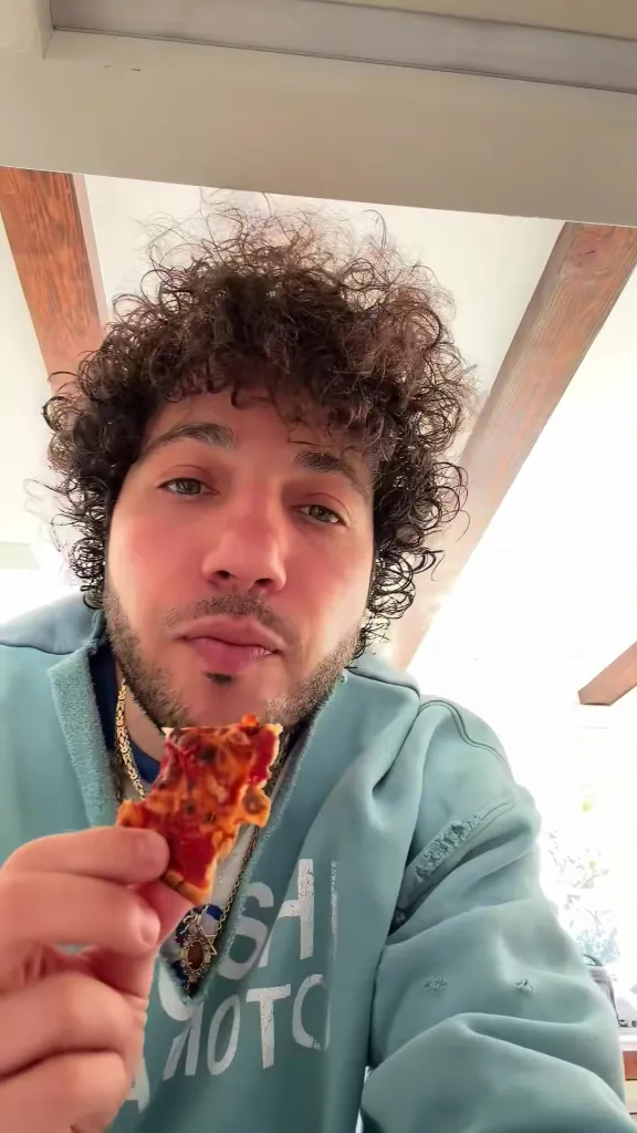 Benny Blanco holding a slice of pizza.