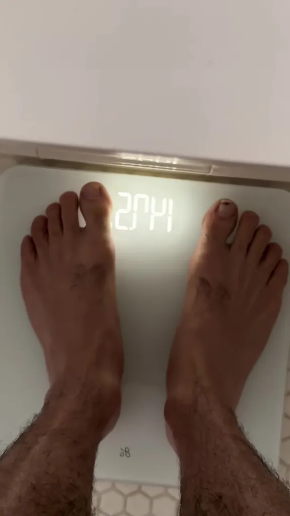 A person's feet on a digital scale showing a weight of 204.1.