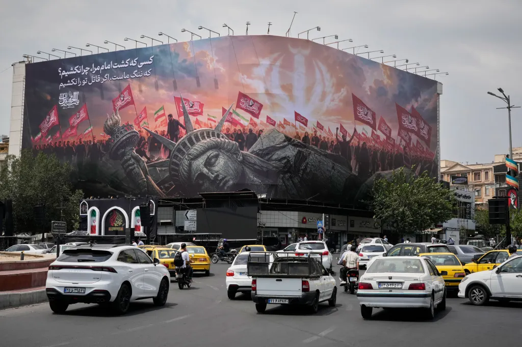 A billboard depicting a fallen Statue of Liberty and crowds carrying Iranian and Shiite flags overlooks Revolution Square as traffic drives by in Tehran, Iran.