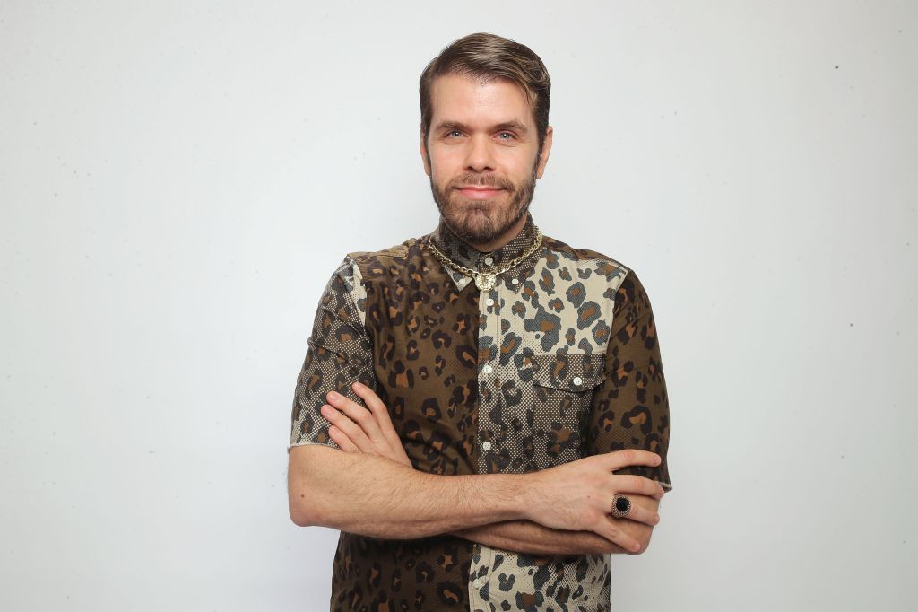Perez Hilton posing for a portrait in a leopard print shirt and gold chain.
