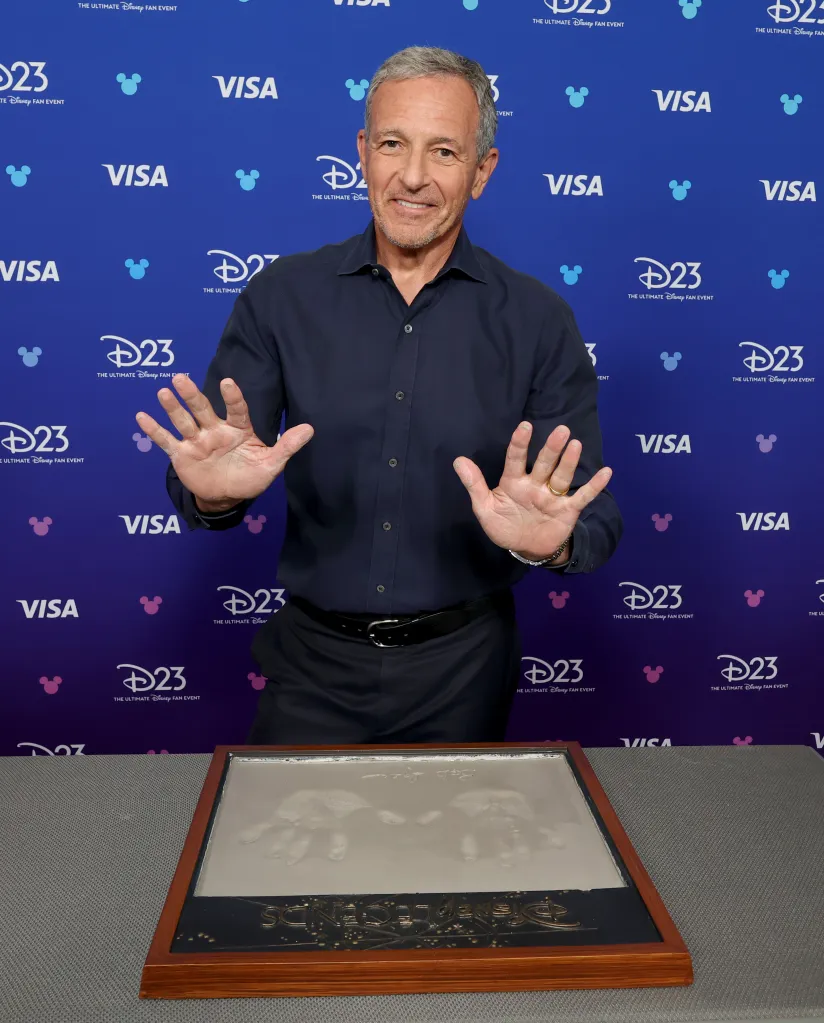 Bob Iger poses with his handprints and signature at the Disney Legends ceremony.