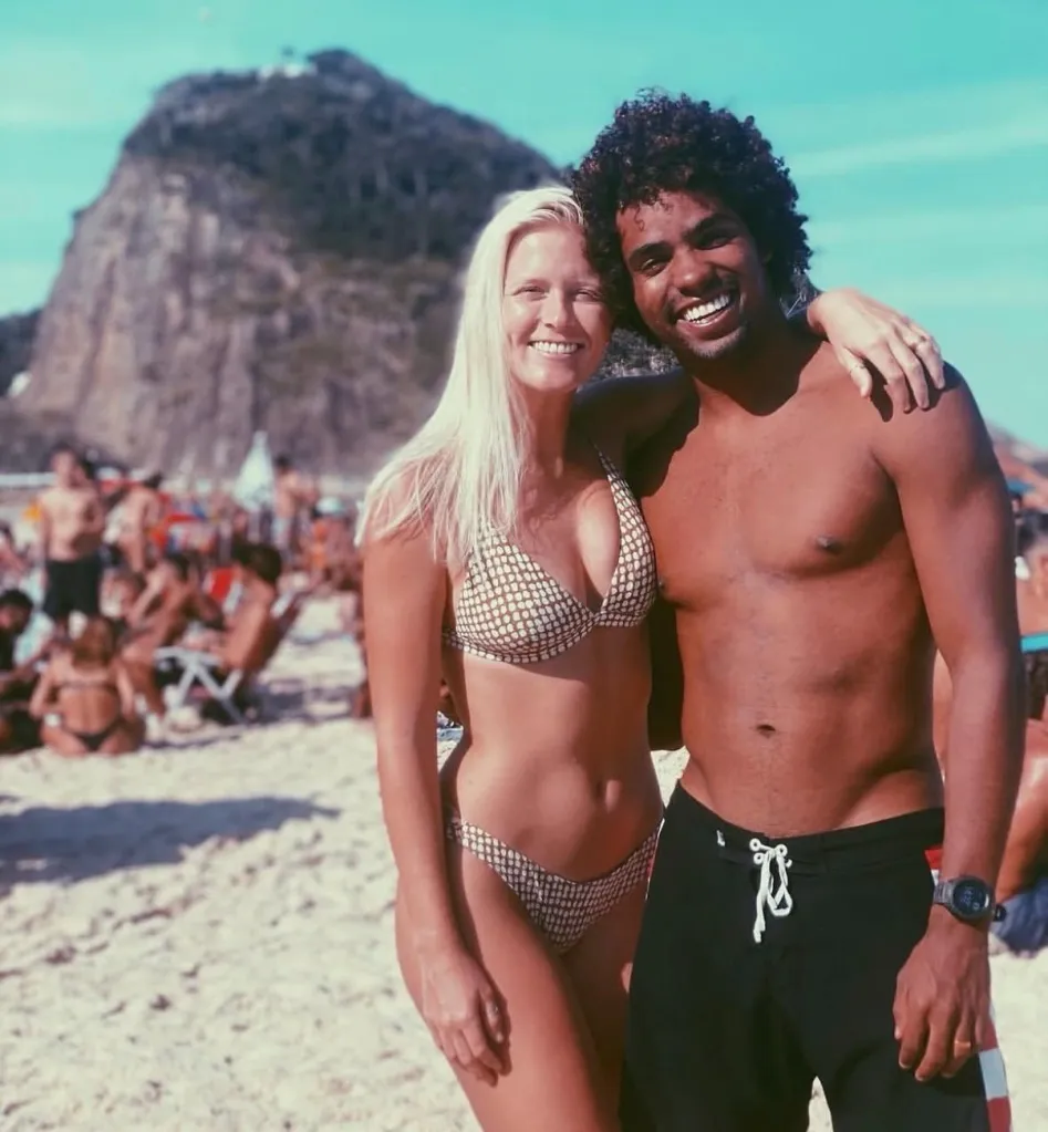 Brazilian surfer Victor Bernardo and his wife, Johnni Bufkin Bernardo, smiling on a beach.