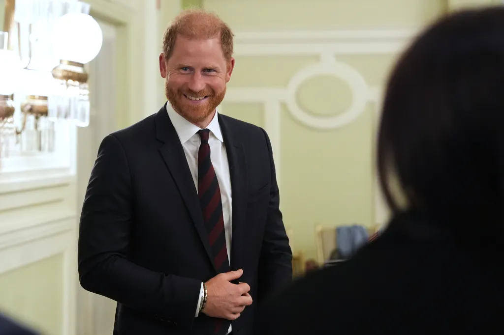 Prince Harry, Duke of Sussex, in a suit, smiling at a roundtable about support for veterans.