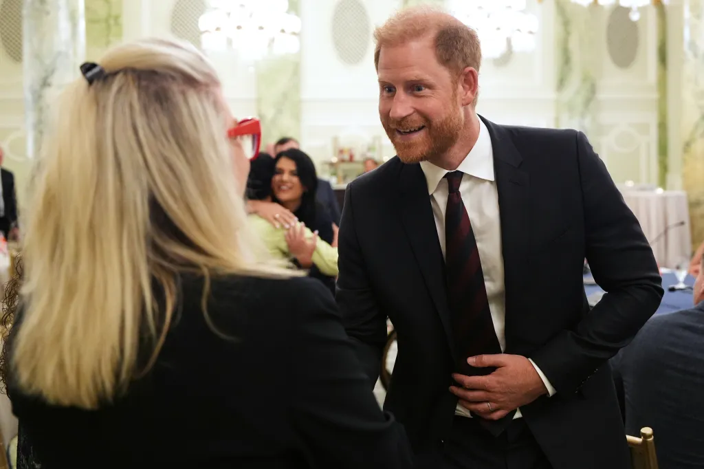 Prince Harry smiles at a woman during a roundtable event for veterans.