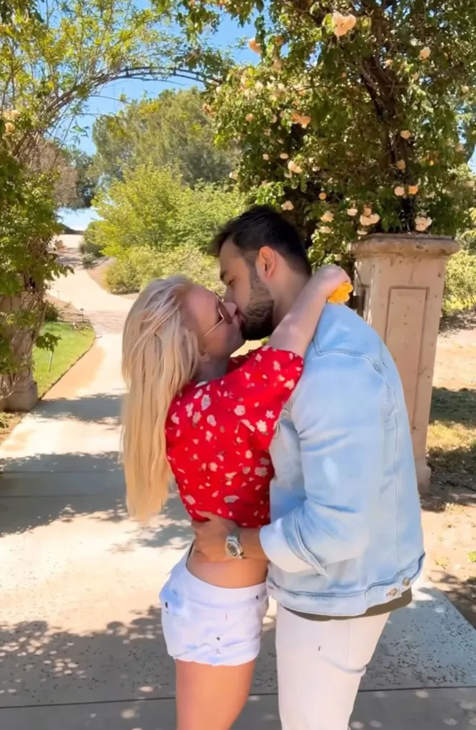 Britney Spears and Sam Asghari share a kiss outdoors.
