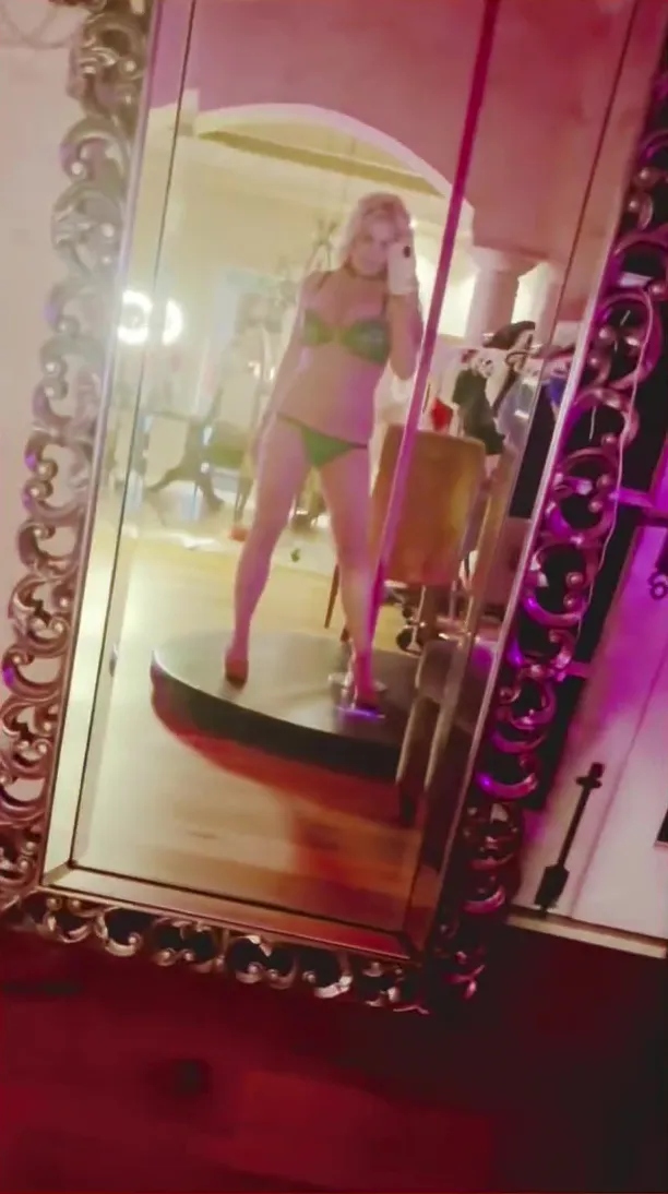 Britney Spears in an embellished bra and black underwear, reflected in a mirror.