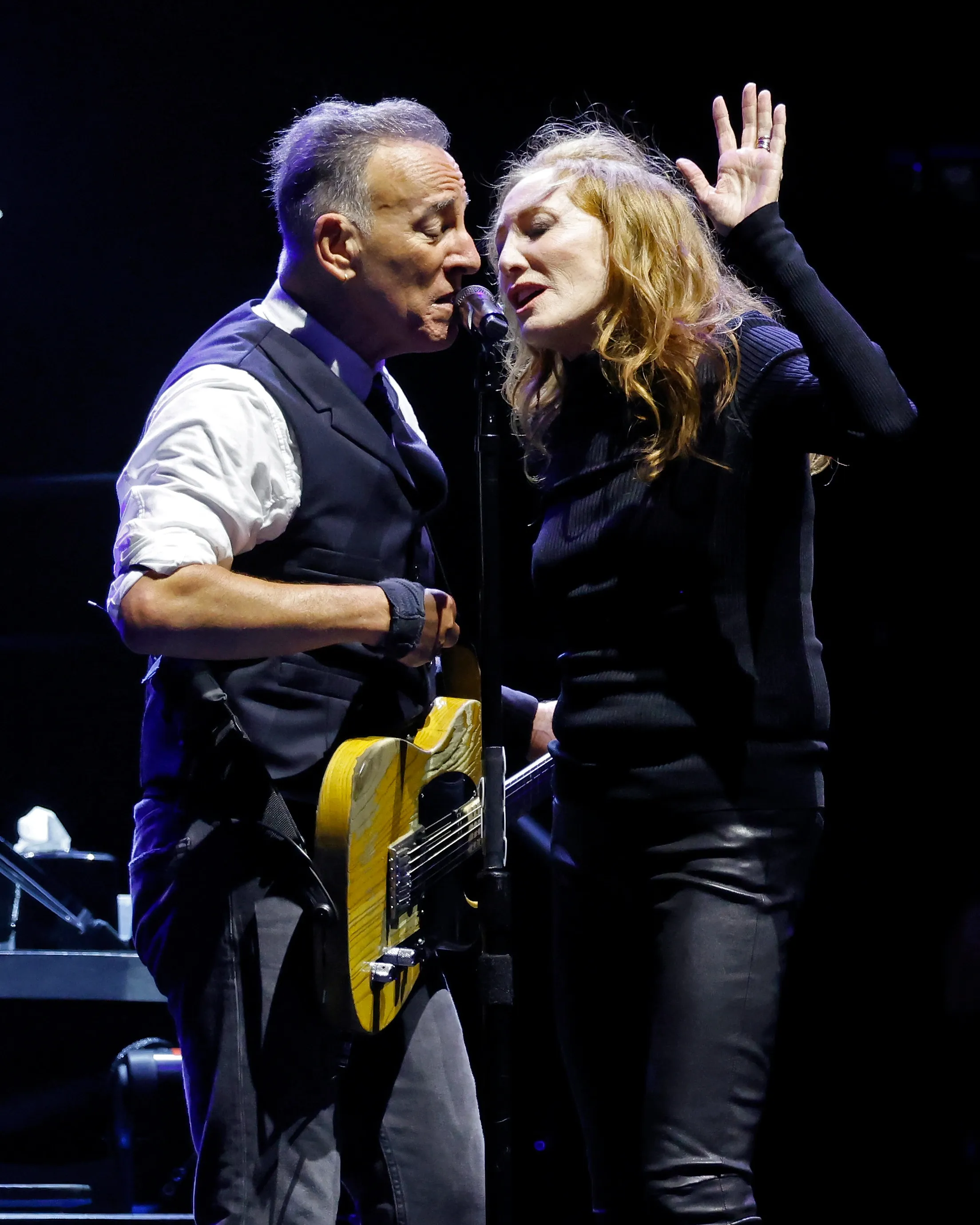 Bruce Springsteen and Patti Scialfa singing together on stage.