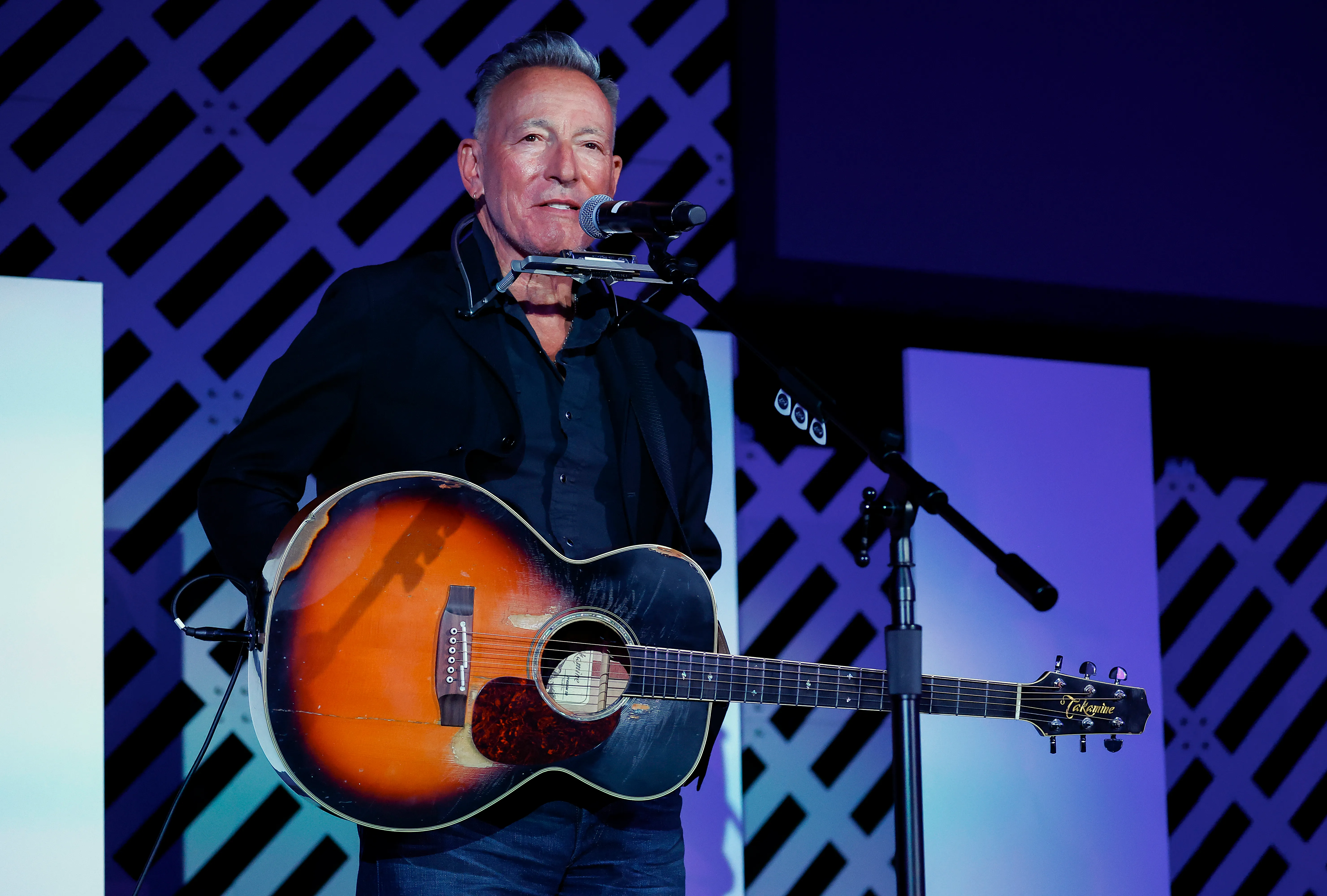 Bruce Springsteen performs with an acoustic guitar and harmonica at the ACLU Awards Ceremony.