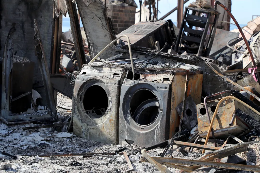 Two burnt and rusted washing machines amidst the debris of Peter Lenkov's fire-damaged home.