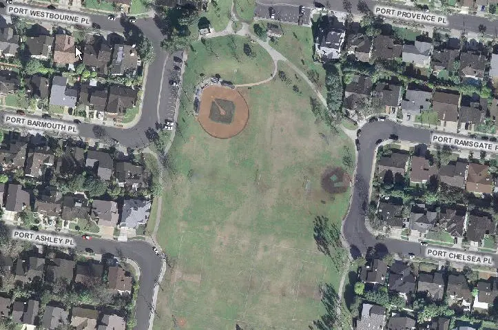 Aerial view of Buffalo Hills Park in Newport Beach, showing a baseball field, green space, surrounding houses, and streets with names like Port Westbourne Pl and Port Ramsgate Pl.